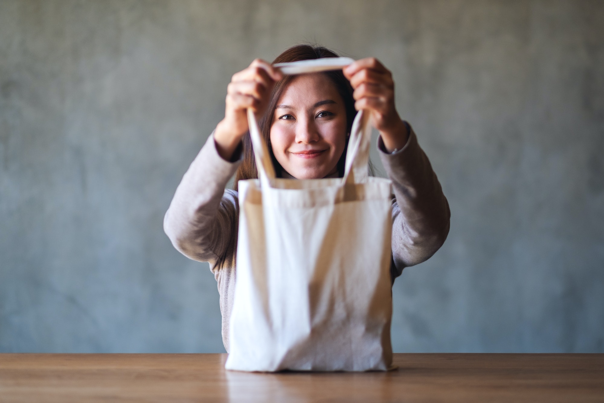 A woman holding a white fabric tote bag for reusable and environment concept